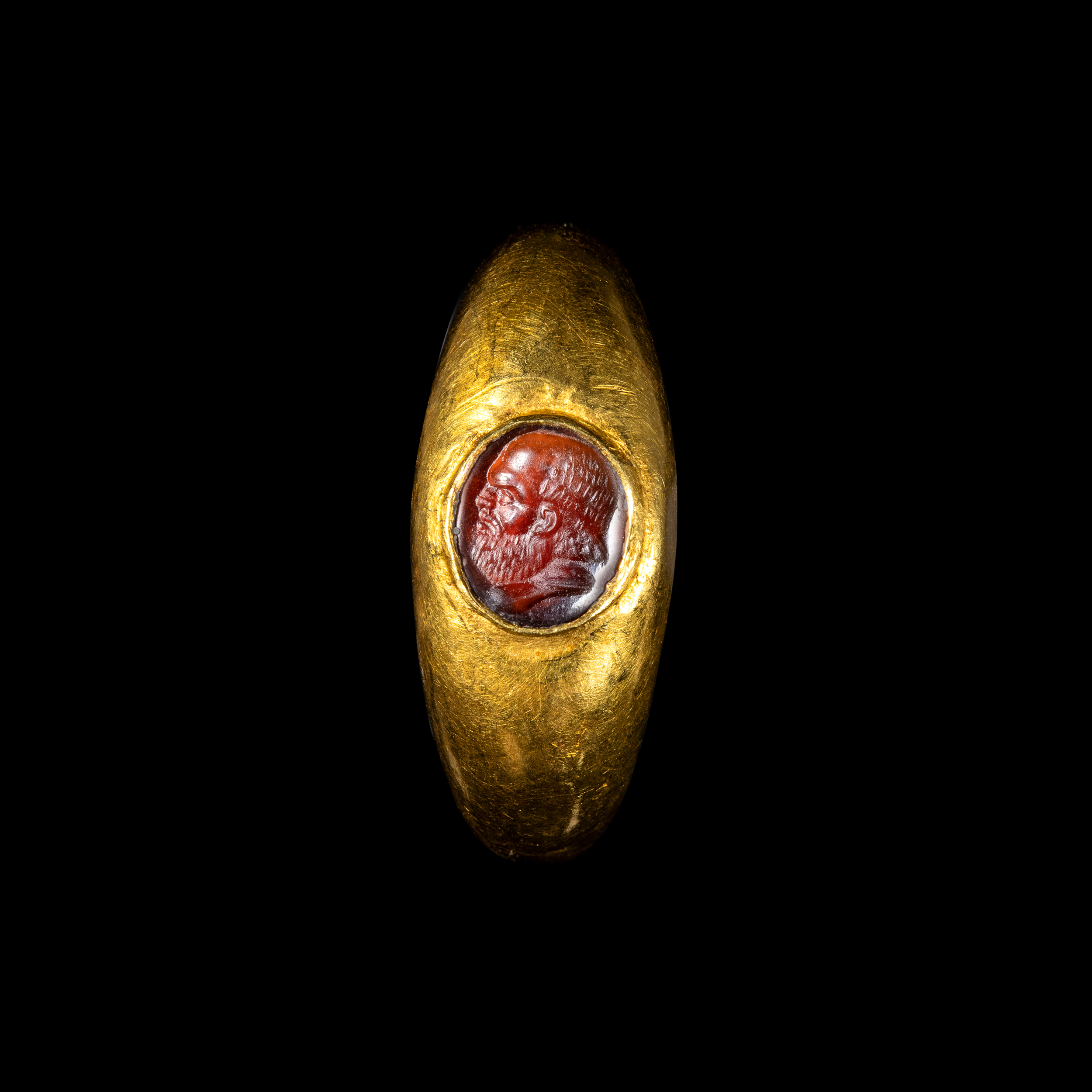 A Roman gold ring set with a garnet intaglio. Male portrait. 